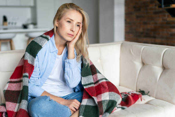 istock Sick and tired female with headache sitting on couch 1348266223