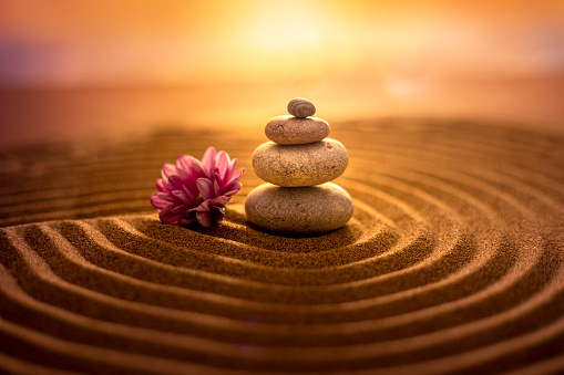 Stack of stones on sand at sunset, creating a relaxed atmosphere of zen harmony