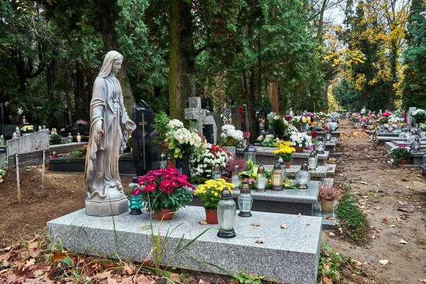 Statue, candles and flowers on graves in a cemetery in Poland