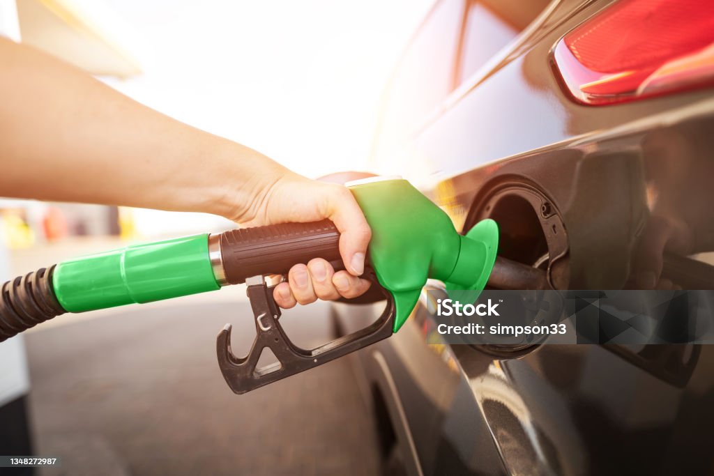 Closeup of man pumping gasoline fuel in car at gas station Closeup of man pumping gasoline fuel in car at gas station. Gas pump nozzle in the fuel tank of a gray car Diesel Fuel Stock Photo
