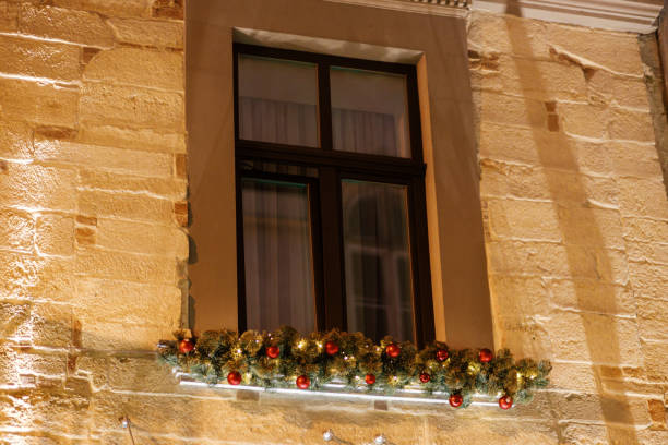 istock Stylish christmas spruce branches with ornaments and lights on building window in evening. Atmospheric magic time. Christmas festive decor for winter holidays 1348273090