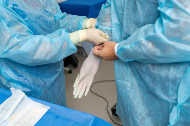 istock Can I help you. Assistant taking on gloves at the main surgeon while working at the hospital during the operation 1348273160