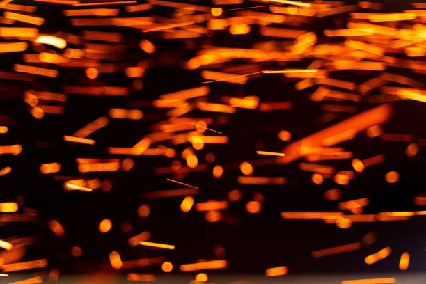 istock Burning red hot sparks fly from large fire in the night sky. Burning embers glowing flying away particles over black background 1348273313