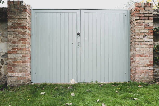 geschlossene und verschlossene gartendoppeltüren in der nähe einer rasenfläche. - tunnel-einfahrt stock-fotos und bilder