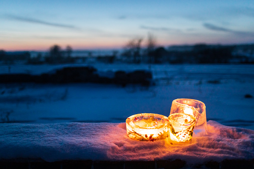Frozen candlesticks made from ice with warm candlelight on a cold winter evening