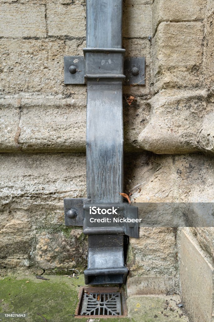 Large leaded metal square drainpipe seen attached to an external stonework wall. Large leaded metal square drainpipe seen attached to an external stonework wall. Attached to a famous English cathedral. Graphite Stock Photo