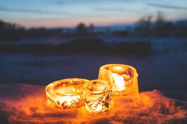 Candlesticks made from ice with warm candlelight on a cold winter evening stock photo