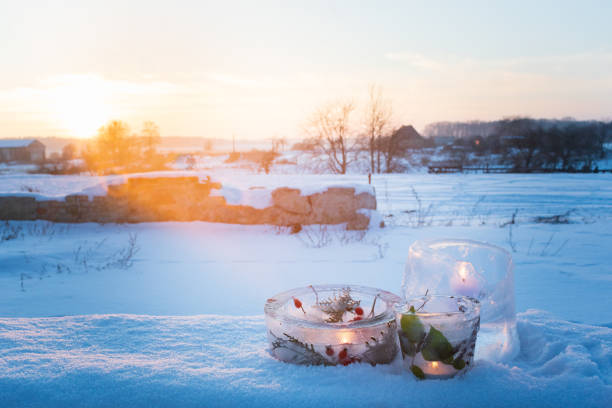 Frozen candlesticks made from ice with warm candlelight on a cold winter evening