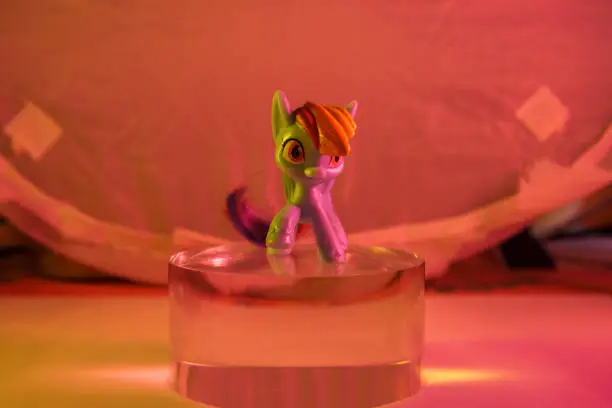 Photo of colorfull toy pony horse on the glass cylinder color background