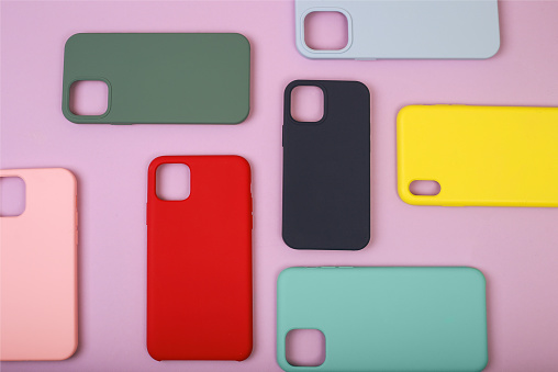 Colored silicone phone cases. Up to date technology.Close up of diverse personal accessory laying on the lavender background. Flat lay