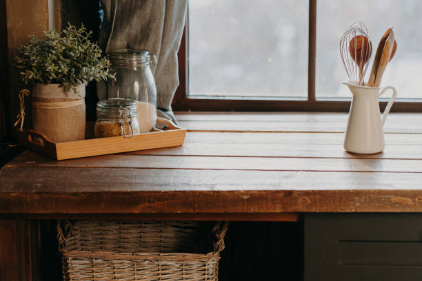 Kitchen utensils in white container on wooden table near window. Home kitchen decor. Kitchenware. Time to cook. Cutlery in room.