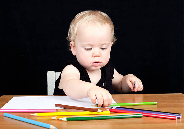 Young girl sitting at desk drawing picture stock photo
