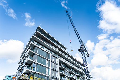 Tower cranes and unfinished buildings, construction cranes on blue sky at construction site in city metropolis.