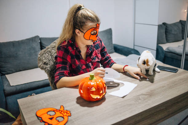 istock Young woman making Halloween decorations at home with her little kitten 1348295422