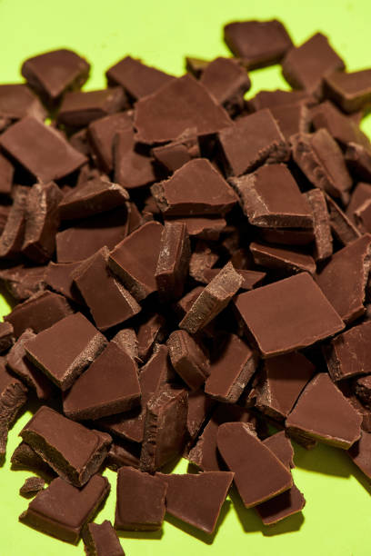 istock Closeup of broken, crushed dark chocolate bars stack isolated over green background 1348296044