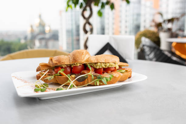 istock Croissant sandwich with avocado, tomatoes on white plate and bright background. Continental style breakfast 1348296412