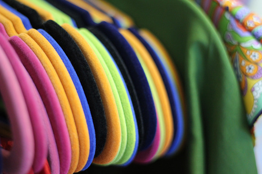 Colored clothes hangers on a bracket, hanging in a row.