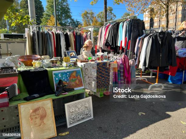 Flea Market Stall With Second Hand Clothes In The Middle There Is An Elderly Lady Sitting And Waiting For Customers Stock Photo - Download Image Now