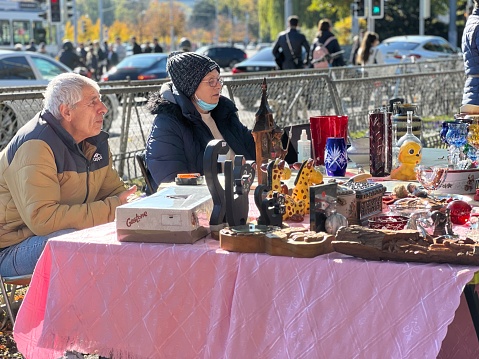 Zurich, Switzerland 10 23 2021 Middle aged couple sitting at their flea market stall. Their merchandise is displayed on a low table and they are waiting for the clients.