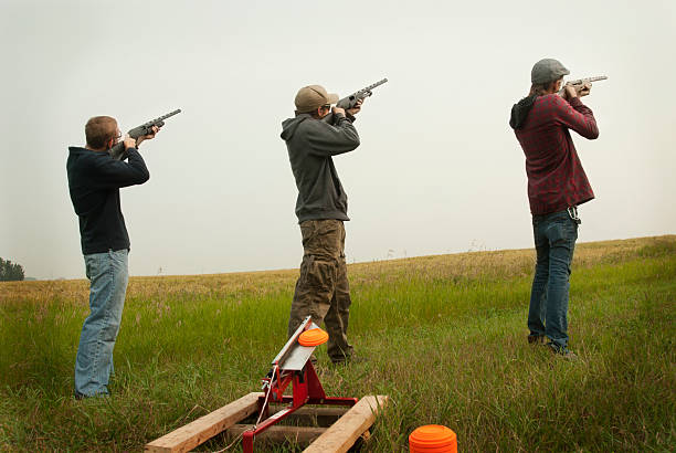 drei männer shooting clay tauben - people shotgun weapon horizontal stock-fotos und bilder