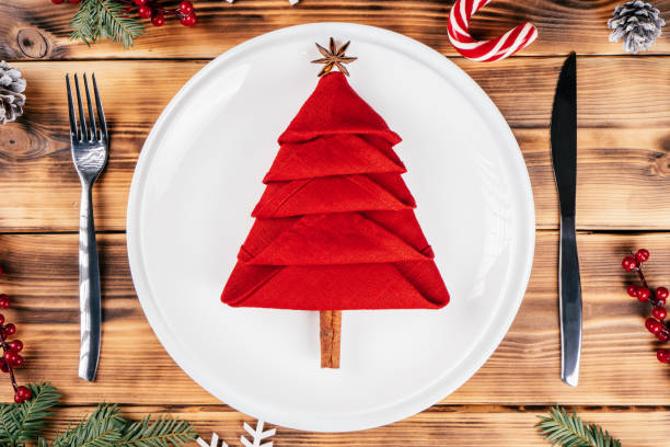 istock Step-by-step tutorial: Fold napkin in shape of Christmas tree. Step 10: Add anise and cinnamon stick for top and trunk 1348314030