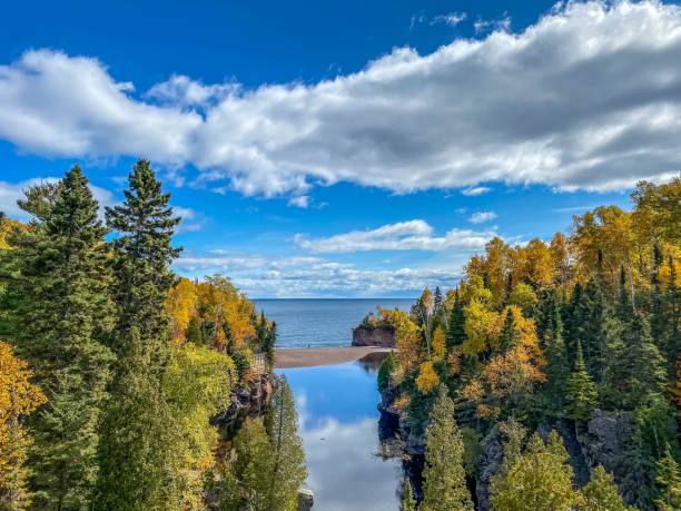 istock Dramatic clouds and blue sky over Autumn Colored Forest along the Baptism River at Tettegouche State Park in Minnesota 1348320959