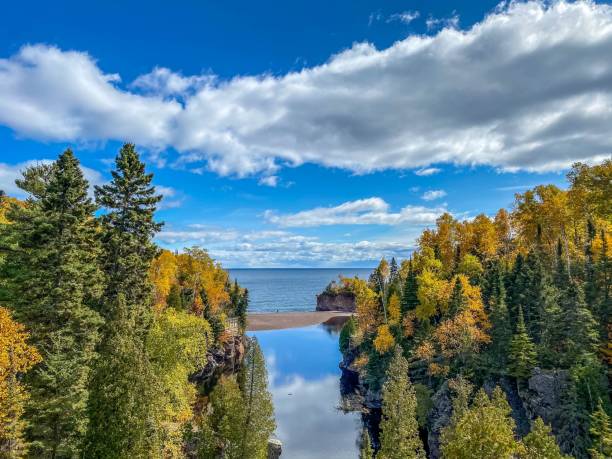 Dramatic clouds and blue sky over Autumn Colored Forest along the Baptism River at Tettegouche State Park in Minnesota stock photo