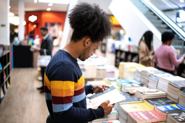 junger mann in einer buchhandlung im einkaufszentrum - bookstore stock-fotos und bilder