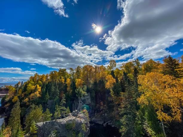 Sun Shining Through the Clouds over Autumn Colored Forest along the Baptism River at Tettegouche State Park in Minnesota