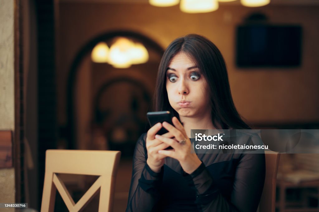 Surprised Young Woman Receiving a Text Message Lady overreacting after looking at her mobile phone Embarrassment Stock Photo