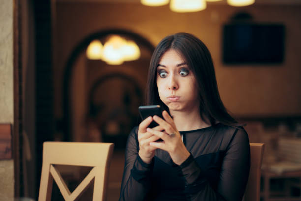 Surprised Young Woman Receiving a Text Message Lady overreacting after looking at her mobile phone sheepish look stock pictures, royalty-free photos & images