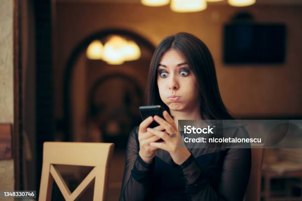 Surprised Young Woman Receiving A Text Message Stock Photo - Download Image Now - Embarrassment, One Woman Only, Mobile Phone