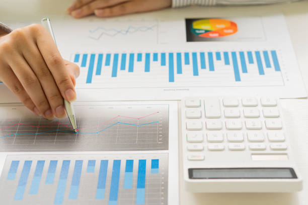 istock businessman holding pen pointing to marketing graph and working on online work concept Group of business people with financial documents and analytical calculators calculate charts while sitting at the office. 1348345185