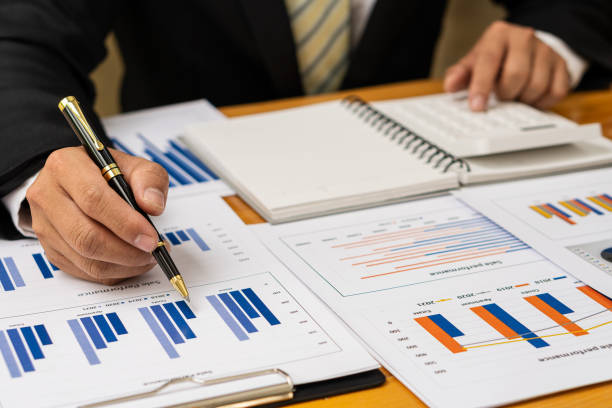 businessman holding pen pointing to marketing graph and working on online work concept Group of business people with financial documents and analytical calculators calculate charts while sitting at the office. hombre de negocios sosteniendo un bolígrafo apuntando al gráfico de marketing y trabajando en el concepto de trabajo en línea grupo de empresarios con documentos financieros y calculadoras analíticas calculan tablas mientras están sentados en la ofici
