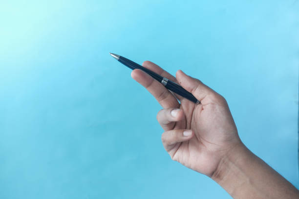 istock hand hols a pen against blue background 1348346958