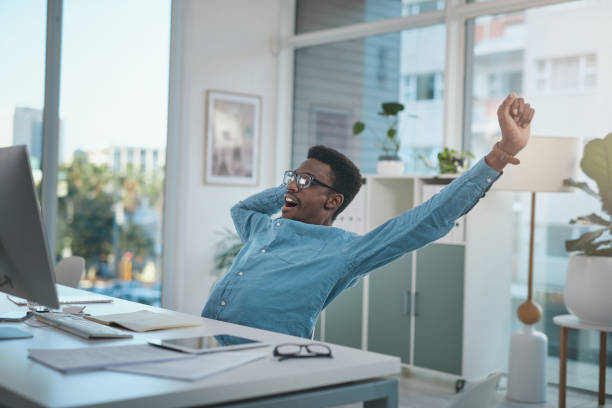 istock Shot of a young businessman looking tired while using a computer at his desk in a modern office 1348347589