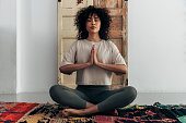 istock Multiracial young woman meditating with hands in prayer at home 1348347815