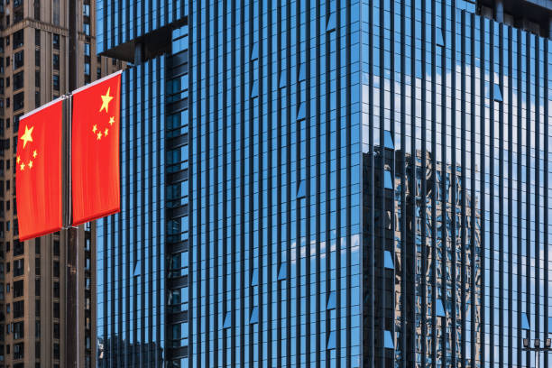 Chinese flag against modern glass skyscraper with reflecting blue sky stock photo