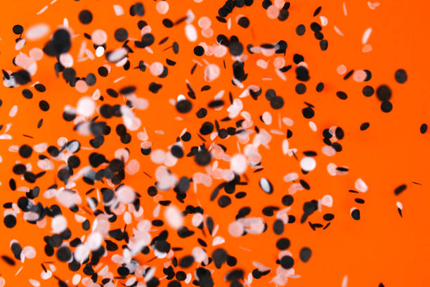 istock White black confetti flying orange background. Halloween party. 1348357727