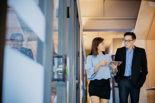istock Asian business people having discussion and walking through office corridor 1348358804