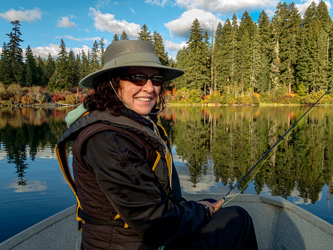 istock Woman Smilig in Rowboat Clear Lake Oregon with Fishing Rod 1348361633
