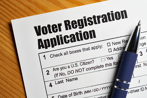 Voter registration application document with pen