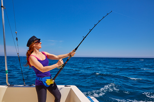 Hermosa mujer chica pescando caña de curricán en bote photo