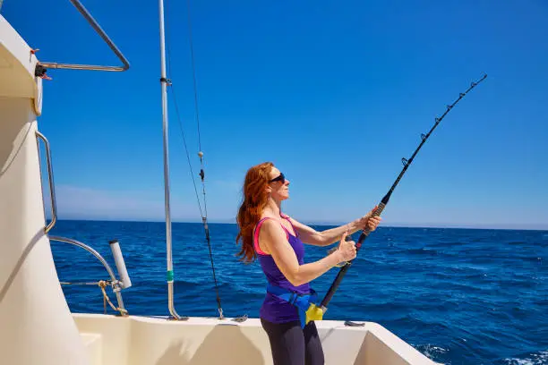 Beautiful woman girl fishing rod trolling in saltwater in a boat trolling
