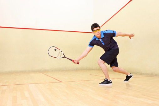 A squash player hitting a ball in a squash court