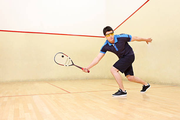 Squash player hitting a ball A squash player hitting a ball in a squash court squash sport stock pictures, royalty-free photos & images