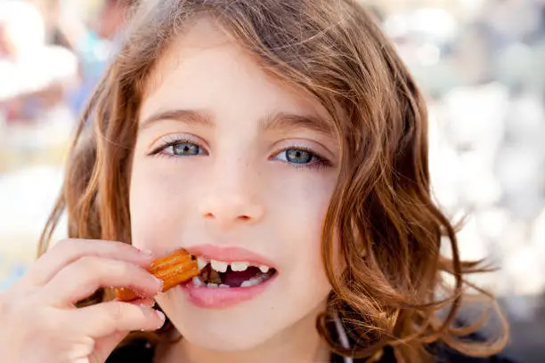 Blue eyes little girl eating churros fried crullers smiling