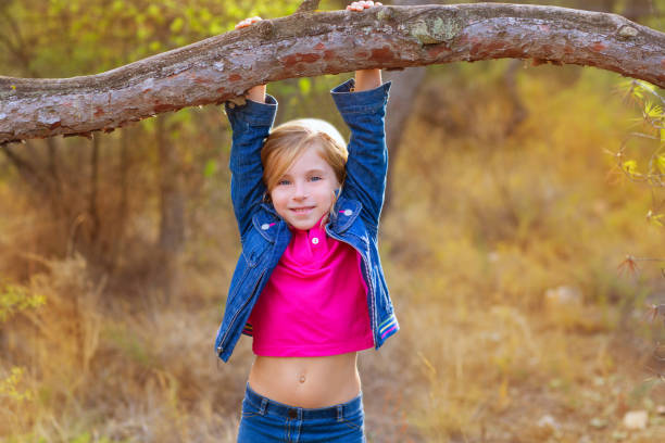 children girl swinging in a trunk in pine forest - preschooler autumn beautiful blond hair imagens e fotografias de stock