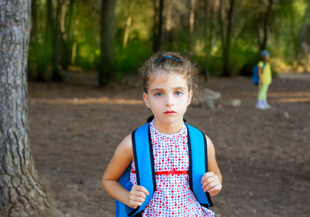 Children girl hiking with backpack in autumn forest