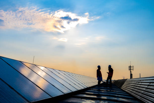 istock Silhouette of two persons standing between rows of solar cells and discussing 1348372234